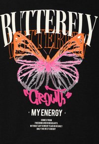 T-shirt nera con una grande grafica di una farfalla multicolore. Il testo in grassetto bianco, arancione e rosa recita "FARFALLA" e "CRESCITA LA MIA ENERGIA."