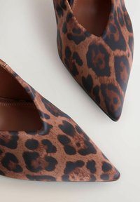 Leopard print høje hæle med spids tå, i en brun og sort farveskema, i et slankt materiale og med udsnit på siden.