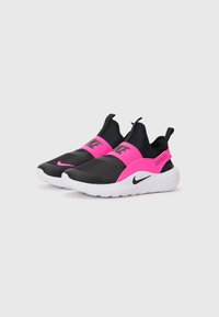Baskets de sport noires et roses à enfiler avec un dessus en mesh, une sangle élastique et une semelle blanche mouchetée. Présente le logo Nike sur la sangle et sur le côté.