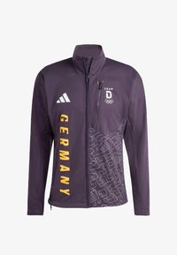 Chaqueta deportiva morada con cuello alto, texto amarillo "GERMANY", múltiples logotipos y un diseño estampado en un lado. Incluye bolsillo delantero con cremallera.