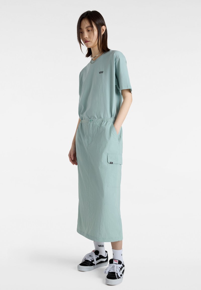 Light teal outfit featuring a short-sleeve T-shirt and ankle-length skirt with an elastic waist and side pocket. Worn with black sneakers.
