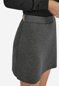 Grauer Strickrock mit taillierter Bundnaht und Nahtdetails. Verfügt über ein kleines Lederetikett am Bund. Weiche Textur und schlichtes Design.