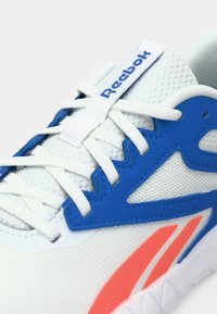 Weißes und blaues Reebok-Sneaker mit weißen Schnürsenkeln, Mesh-Obermaterial und einem rosa Reebok-Logo an der Seite.