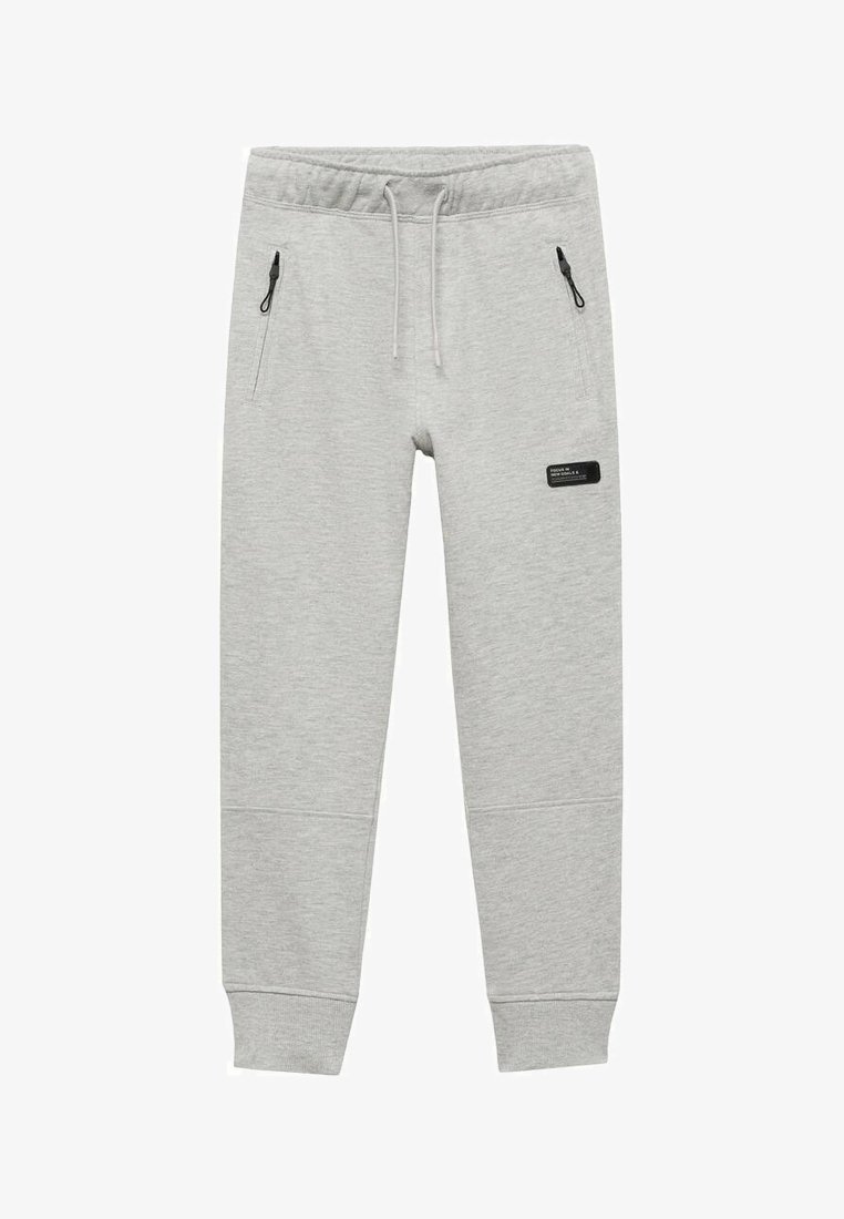 Šedé bavlněné tepláky s elastickým pasem, šňůrkou na stažení a bočními zipovými kapsami. Na levém stehně se nachází černá nášivka.