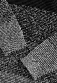 Strickpullover in verschiedenen Grautönen, mit Rippbündchen und einem strukturierten horizontalen Design. Weiches Material mit einem geschichteten Aussehen.