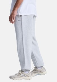 Grijze joggingsbroek van zachte stof, met een losse pasvorm, zijzakken en een klein logo-accent op de linker bovenbeen.