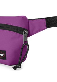 Sacchetto di tessuto viola con zip nera e tracolla nera. Presenta una finitura testurizzata, un'etichetta con logo e un dettaglio con cordoncino. Design compatto.