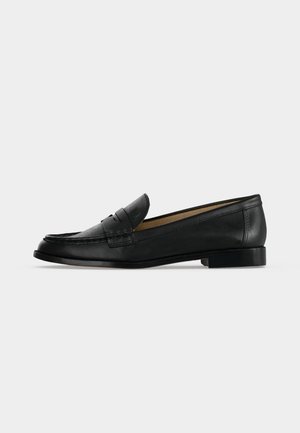 Mocassin penny noir en cuir avec talon bas, surpiqûres moc toe et design slip-on vu de profil sur un fond clair.