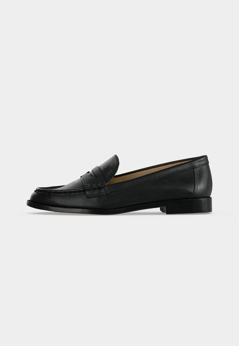 Μαύρο δερμάτινο penny loafer με χαμηλό τακούνι, ραφές moc toe και σχεδιασμό slip-on, εμφανίζεται από το πλάι σε ανοιχτό φόντο.