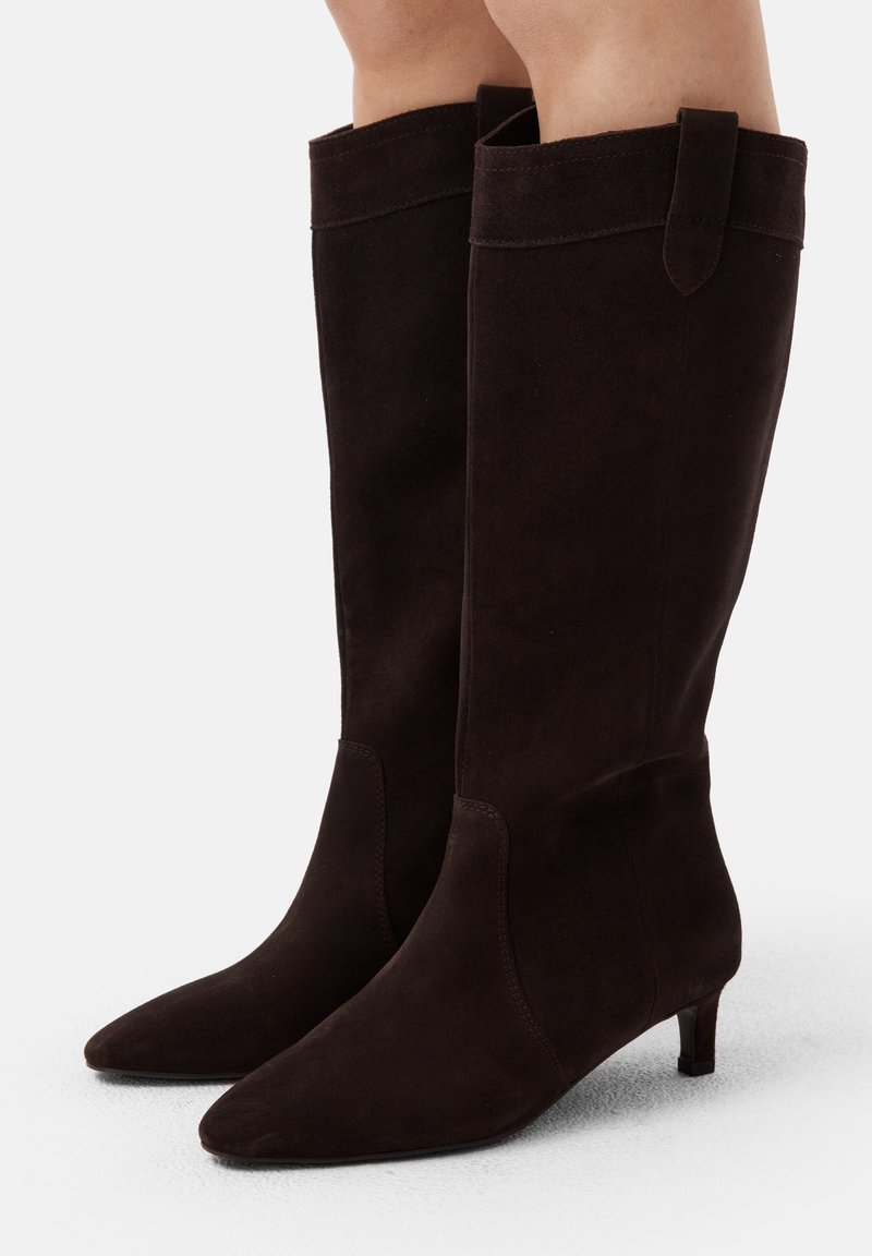 Stivali al ginocchio in suede marrone con punta appuntita, tacco basso e dettagli cuciti sulla parte superiore. Tessuto liscio con un design verticale.
