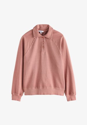 Vaaleanpunainen, raglan-hihainen neulepaita, jossa on kauluspaita ja kolmipainikekaulus. Pehmeä kangas ribbaustaskuilla ja helmalla.