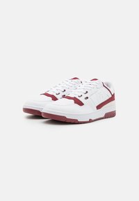Sneakers bianchi con accenti bordeaux, realizzati in materiale sintetico liscio. Presentano lacci, colletto imbottito e una suola in gomma texturizzata.
