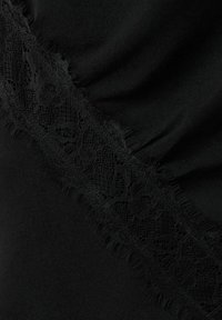 Țesătură neagră cu o panglică diagonală de dantelă florală elaborată și pliuri moi care creează textură și profunzime.