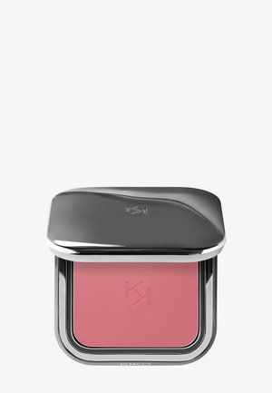 Kompakt blush i et blankt sølv-etui, med et mykt rosa pudderinnhold, preget logo og en polert, buet toppseksjon.