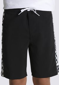Pantaloni da bagno neri con vita regolabile, caratterizzati da un motivo a scacchi lungo i lati, realizzati in materiale leggero con una texture liscia.