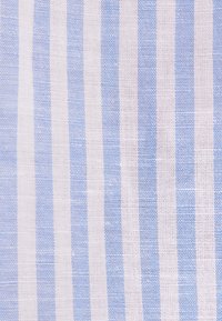 Gros plan d’un tissu rayé vertical blanc et bleu clair avec une texture tissée.
