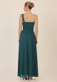 Tee-grüne, einseitige Abendgarderobe mit gerafftem Oberteil und fließendem Rock. Der Stoff ist weich, leicht und am Saum leicht durchsichtig.