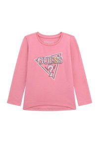 Vaaleanpunainen pitkähihainen paita, joka on valmistettu luomupuuvillasta. Paidassa on kolmiomainen hope glitter -kuvio, jossa on "GUESS"-tekstiä ja kysymysmerkkejä.