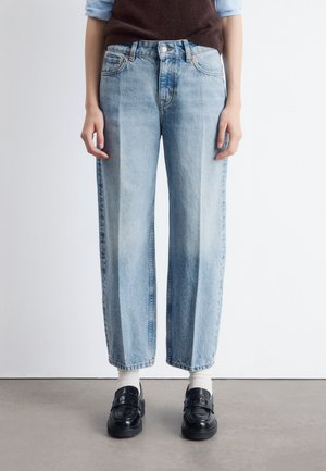 Hellblaue, hochgeschnittene Jeans mit gerader, lockerer Passform. Verfügt über leichte Ausbleichungen, fünf Taschen und einen Metallknopfverschluss.