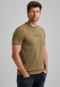 Olivgrünes Baumwoll-T-Shirt mit kurzen Ärmeln und rundem Halsausschnitt, mit "PME LEGEND AMERICAN CLASSIC" in einer dunkleren Farbe bedruckt.