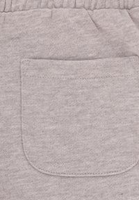 Tessuto di cotone grigio con una singola tasca posteriore dai bordi cuciti, texture morbida e vestibilità rilassata.