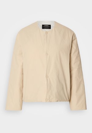 Veste bomber beige, légère, avec un col rond, deux fermetures à boutons à l'avant et un tissu légèrement texturé. Design minimaliste.