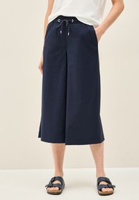 Navy culottebroekjes gemaakt van zachte stof, met een opvallende tailleband, zijzakken en een relaxed fit. Gecombineerd met navy sandalen.