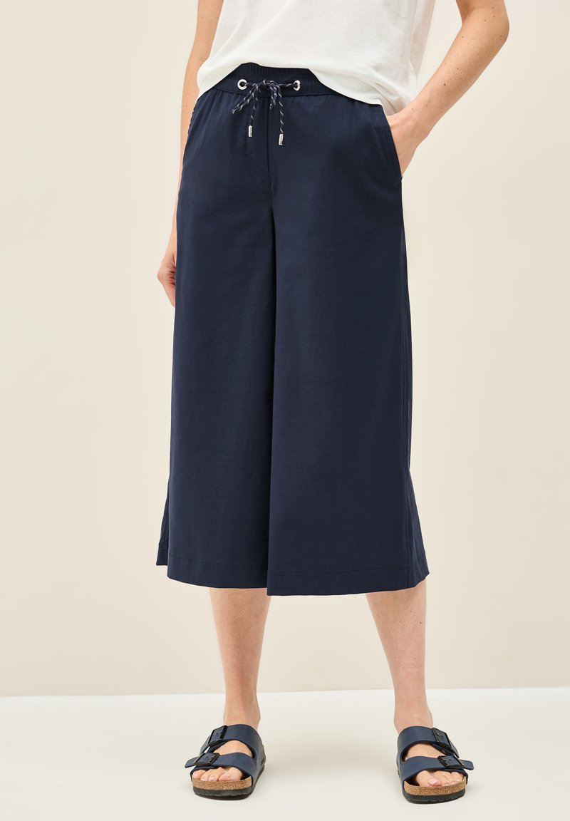 Navy culottebroekjes gemaakt van zachte stof, met een opvallende tailleband, zijzakken en een relaxed fit. Gecombineerd met navy sandalen.