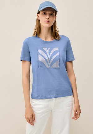Lysblå bomulds t-shirt med korte ærmer og en rund halsudskæring. Har et grafisk print med lodrette linjer og tekst i kontrastfarver.