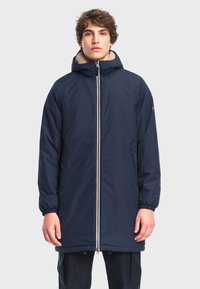 Marineblauwe parka met een rits aan de voorkant, elastische manchetten en een capuchon met nep-vachtvoering. Voorzien van zijzakken en een recht gesneden ontwerp.