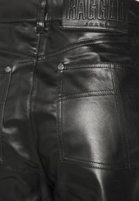 Jeans in pelle nera con una texture liscia, dotati di due tasche posteriori e un'etichetta con il logo del marchio in rilievo alla vita.