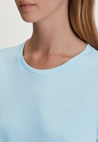 Lichtblauwe katoenen t-shirt met een ronde halslijn en korte mouwen; gladde textuur en minimale naden voor een schone afwerking.