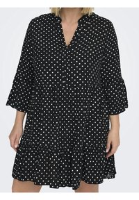 Schwarzes Polka-Dot-Kleid mit V-Ausschnitt, Dreiviertelärmeln und gestuftem Rüschensaum. Aus leichtem Material gefertigt. Weiße Polka-Punkte überall.