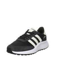 Svart och grå sneaker med textil- och mockamaterial, tre vita ränder och en tjock vit mellansula; gummiyttersula med greppmönster.