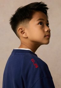 Jūras zila T-kreklī ar sarkanu "SD-JPN" izšuvumu uz pleca, izgatavots no kokvilnas ar klasisku apaļu kakla izgriezumu un īsām piedurknēm.