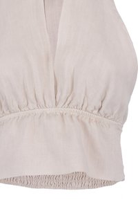 Lichtbeige linnen top met een diepe V-hals, een verzamelde taille en een gerimpelde zoom. Soepele textuur met een subtiel geweven patroon.