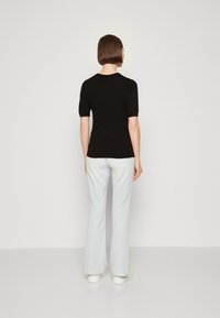 Top negro de manga corta combinado con pantalones acampanados de rayas azul claro y blanco. Los pantalones tienen una textura de algodón suave y un diseño ajustado.