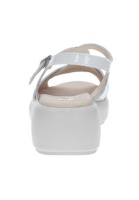 Sandalias de charol blancas con tiras finas y una suela de plataforma blanca. Incluyen un cierre de hebilla y una plantilla acolchada.