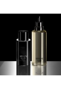 Dos botellas de Armani Code Parfum, una negra con tapa y una transparente con pulverizador, sobre una superficie reflectante con fondo negro.