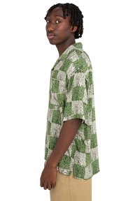 Camisa de manga corta en patrón de cuadros verde y blanco con textura de madera; corte relajado; diseño abotonado; estilo de cuello.