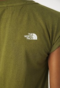 Olivgrön kortärmad t-shirt i mjukt tyg, med en vit logotyp av "THE NORTH FACE" på baksidan nära axeln.