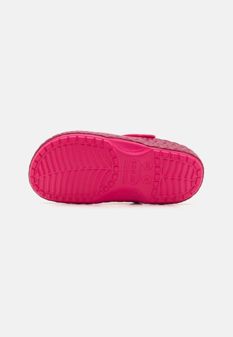 Suela de zapato de goma rosa brillante con un patrón de textura, que presenta acentos circulares elevados y una marca. Diseño achatado para uso casual.