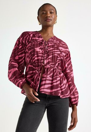 Blus med blommönster i lättviktsmaterial i burgundy och rosa, med långa ärmar, v-ringning och snörningsdetalj vid midjan.