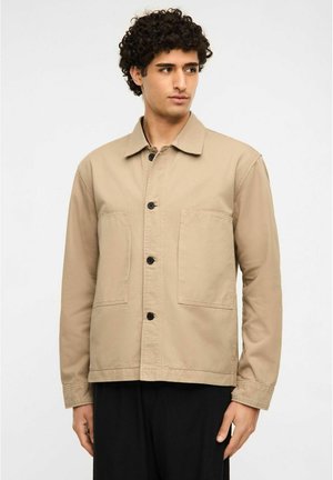 Beige lærredsjakke med krave, knaplukning foran og to store påsyede lommer. Har lange ærmer og en afslappet pasform.
