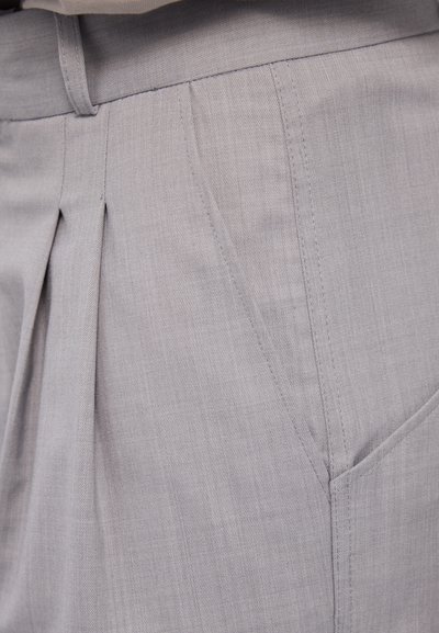 Light gray tailored trousers featuring a smooth, textured fabric with side pleats and angled pockets. Clean lines and subtle stitching.