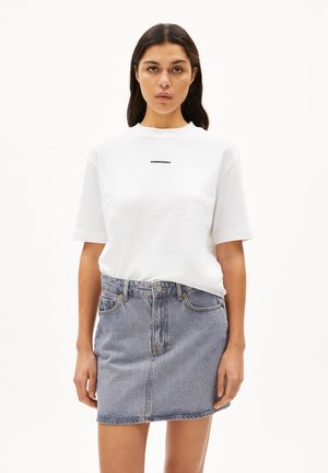 T-shirt blanc à manches courtes avec un logo en texte noir, associé à une jupe en denim bleu clair. L'ensemble présente un design décontracté classique.