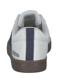 Vita sneakers med marinblå accenter, slät syntetisk material, rund tå, vadderad krage och gummisula med ett texturerat mönster.