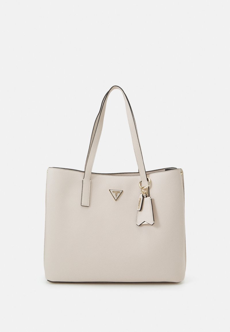 Sac cabas en cuir beige avec deux poignées, un logo triangulaire et un porte-clés décoratif. Texture lisse, design minimaliste et accents dorés.