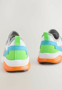 Sportschuhe mit einem grauen Stoff-Obermaterial, grünen und blauen Akzenten, orangefarbener Sohle und strukturiertem weißen Fersenbereich mit Zugschnur.
