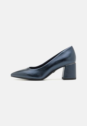 Soulier à talon haut à bout pointu en cuir verni bleu foncé. Dispose d'un talon épais avec un accent métallique. Texture lisse avec un design épuré.
